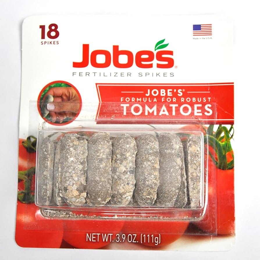 Jobe’s tomato fertilizer spikes placed in soil beside a tomato plant in a container