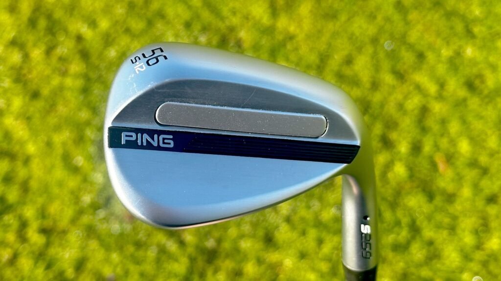 Ping s259 wedge behind a golf ball near the fringe with a tight, square setup