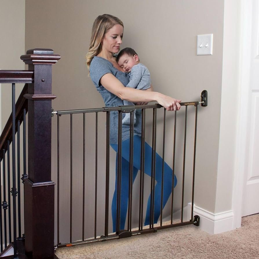 Hardware-mounted Toddleroo baby gate at the top of a staircase with swing-open door and bronze finish